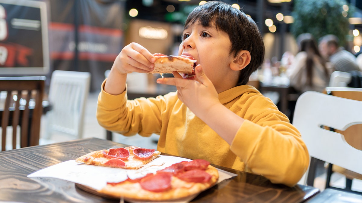 Enfant mangeant une pizza au restaurant