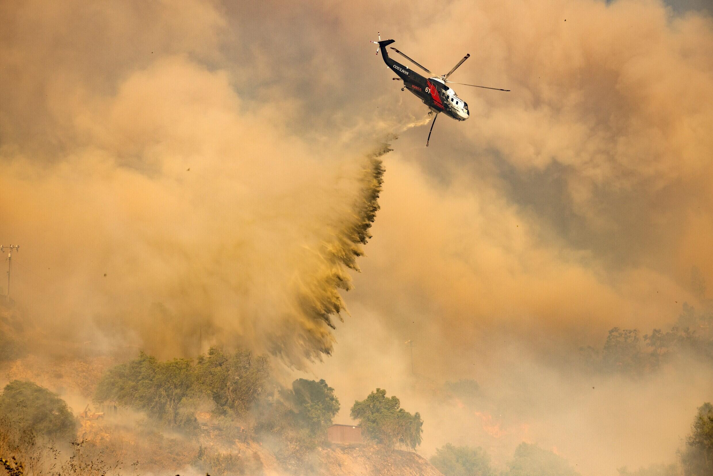 Un hélicoptère effectue un largage d'eau au-dessus du 'Mountain Fire' à Camarillo, en Californie, mercredi 6 novembre 2024.