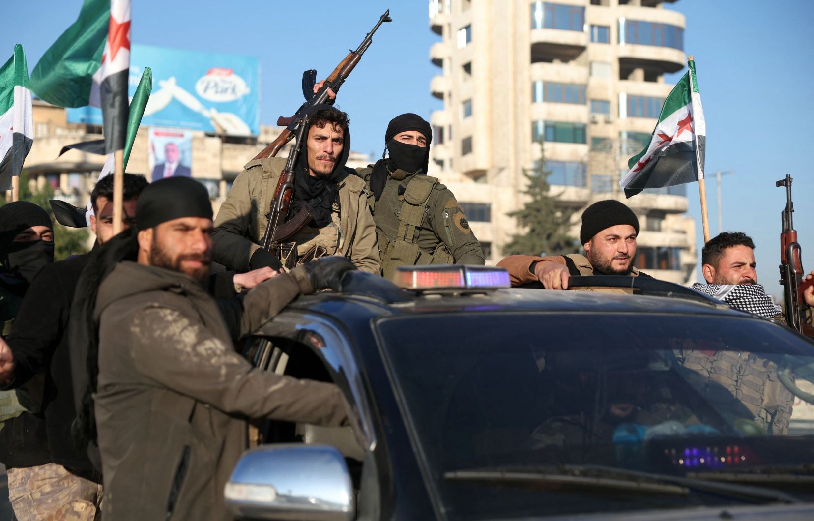 Des combattants anti-gouvernementaux brandissent leurs armes alors qu’ils conduisent un véhicule dans la ville d’Alep, au nord de la Syrie, le 30 novembre 2024.